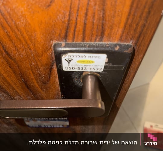 ידית דלת כניסה עם מדבקת שירות של מנעולן